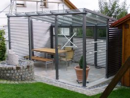 Gartenlaube aus Stahl verzinkt und lackiert, mit Glasdach. Wandverkleidung aus                    Wellblech in Aluminium und teilweise aus Glas. 