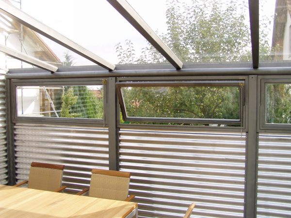 Gartenlaube aus Stahl verzinkt und lackiert, mit Glasdach. Wandverkleidung aus                    Wellblech in Aluminium und teilweise aus Glas.