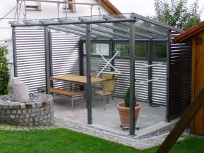 Gartenlaube aus Stahl verzinkt und lackiert, mit Glasdach. Wandverkleidung aus                    Wellblech in Aluminium und teilweise aus Glas.