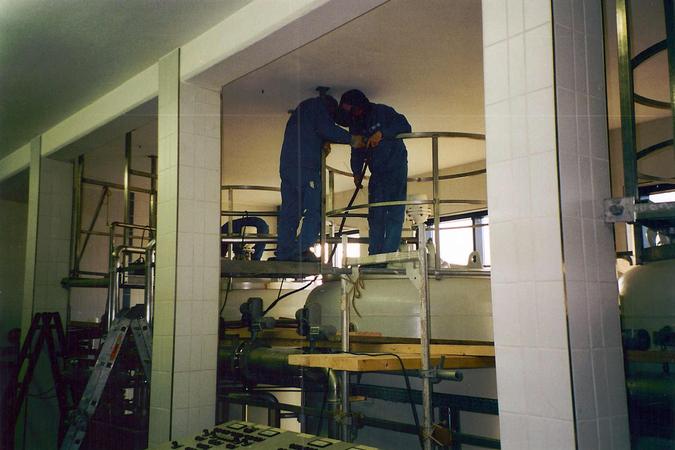 Montage einer runden Arbeitsb&uuml;hne aus Edelstahl auf einem Beh&auml;lter