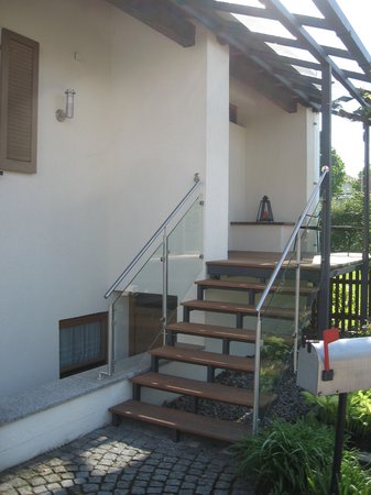 Hauseingansgüberdachung mit Stahltreppe verzinkt lackiert, Geländer aus Edelstahl und Glas, Belag                   aus Tropenholz