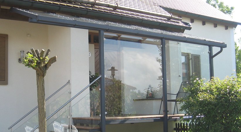 Hauseingansgüberdachung mit Stahltreppe verzinkt lackiert, Geländer aus Edelstahl und Glas, Belag                   aus Tropenholz