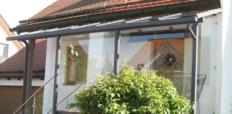 Hauseingansgüberdachung mit Stahltreppe verzinkt lackiert, Geländer aus Edelstahl und Glas, Belag                   aus Tropenholz