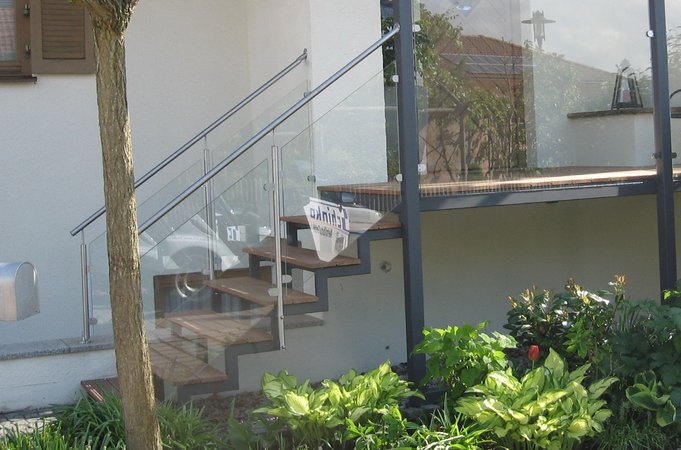Hauseingansgüberdachung mit Stahltreppe verzinkt lackiert, Geländer aus Edelstahl und Glas, Belag                   aus Tropenholz