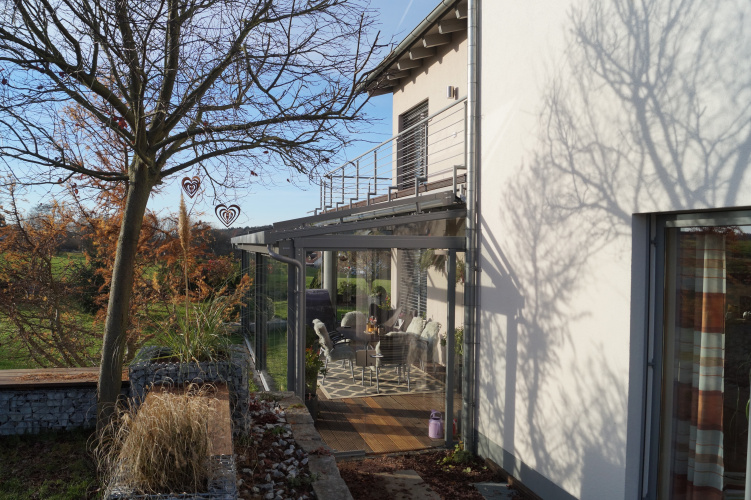Terrassenüberdachung mit aussenliegender Dach- und Wand- Markise. Glasschiebewand mit bodenebener Führungsschiene zum kompletten öffnen der Glaswand