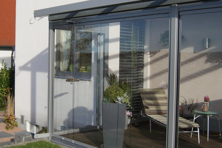 Terrassenüberdachung mit aussenliegender Dach- und Wand- Markise. Glasschiebewand mit bodenebener Führungsschiene zum kompletten öffnen der Glaswand