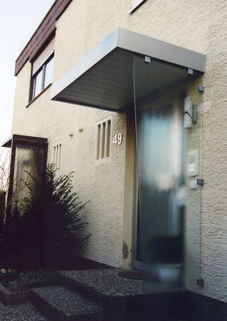 Eingangsüberdachung mit Blechverblendung und Holzansicht, seitlicher                        Windschutz nur mit Glashalterungen befestigt