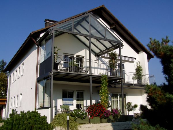 Balkonanbau mit verglaster Überdachung, seitlichem Windschutz,                              Sonnenrollo, Geländer mit Edelstahlhandlauf