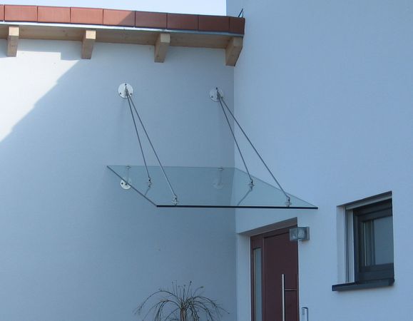 Eingangsüberdachung schräg abgehängt aus Edelstahl mit                                     Verglasung