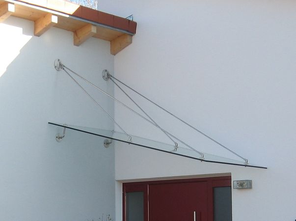 Eingangsüberdachung schräg abgehängt aus Edelstahl mit                                     Verglasung